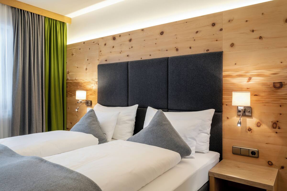 A double bed with a wooden headboard and two bedside lamps.