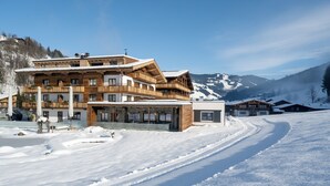 Un edificio de madera grande con varios balcones y una pista de esquí al fondo.