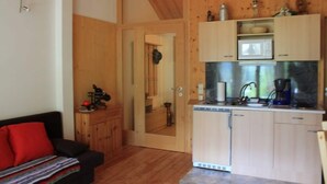 Une cuisine de taille réduite, dotée de meubles en bois, d’un four à micro-ondes et d’une machine à café.