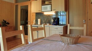 Une cuisine compacte dotée de meubles en bois, d’un four à micro-ondes, d’une machine à café et d’un coin repas avec une table et des chaises.