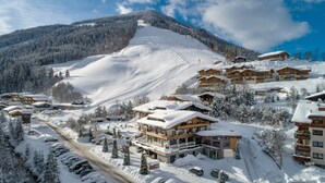 A snow-covered ski resort with multiple chalet-style buildings, a ski slope, and a parking area.