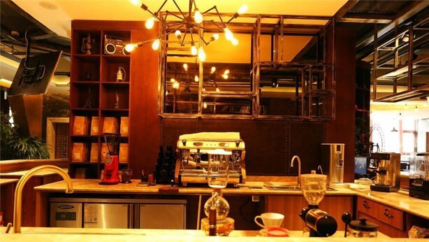 A modern kitchen with a built-in espresso machine, a coffee grinder, and a wine glass on the counter.