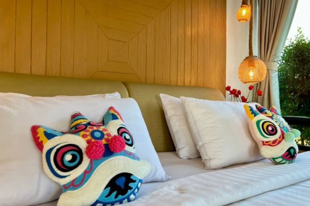 Un letto con biancheria bianca e due cuscini colorati con faccine di animali.