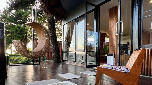 A spa area with a hot tub, wooden lounge chairs, and a large glass door leading to a private room. - Bella Lunar Villa (Mae Fa Luang)