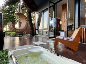 Un área de spa con un jacuzzi, sillones de madera y un amplio ventanal que da a una habitación privada.