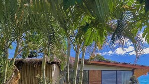 A tropical resort with a thatched-roof structure, a modern building with large windows, and lush greenery. - Bella Lunar Villa (Mae Fa Luang)
