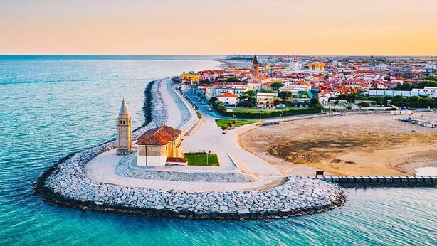 A coastal town with a prominent church, a beach, and a stone pier. - Relaxing Coastal Stay in Lido Altanea (Caorle (VE))