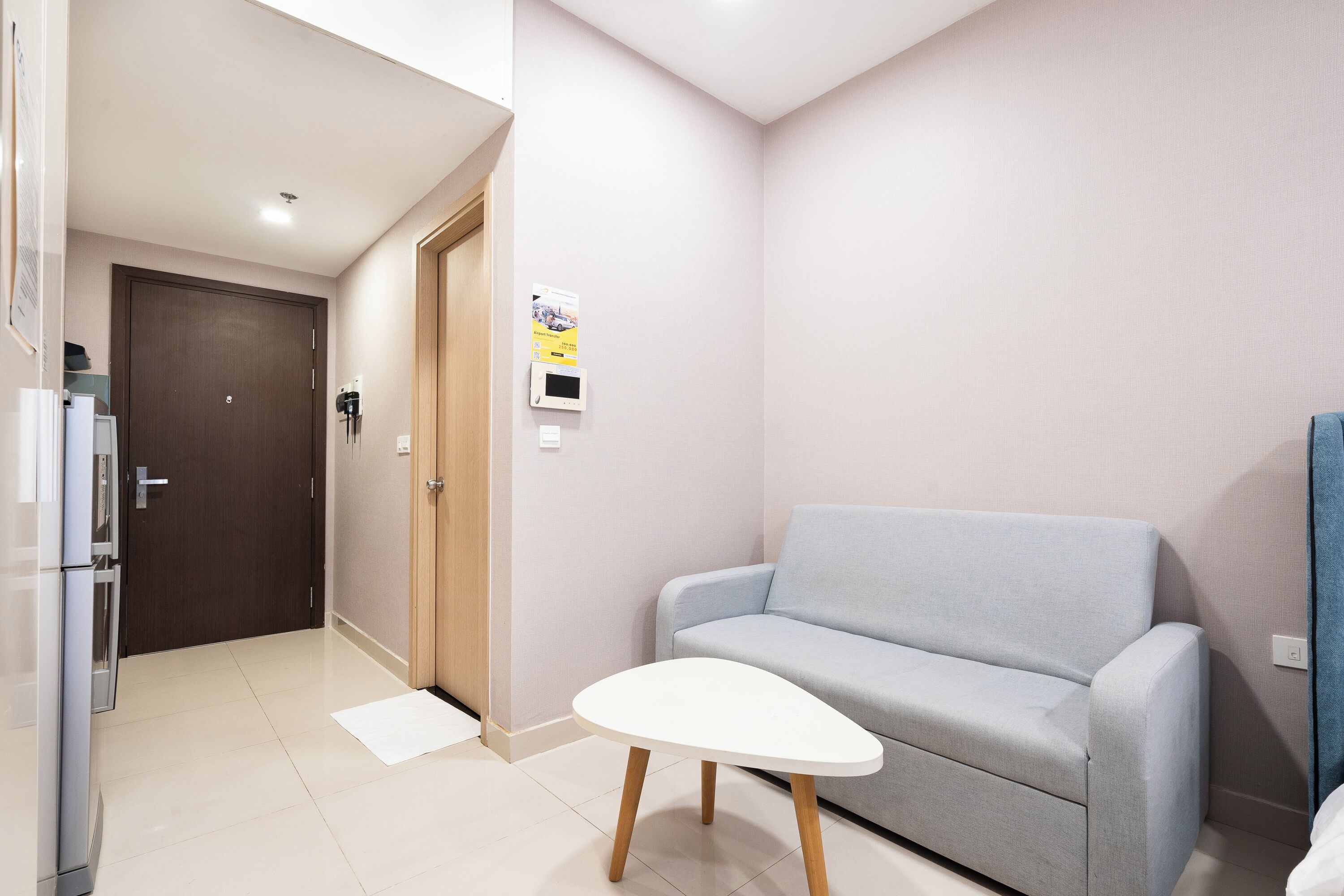 Una sala de estar moderna con un sofá gris, una mesa de centro blanca y una puerta que da a otra habitación.
