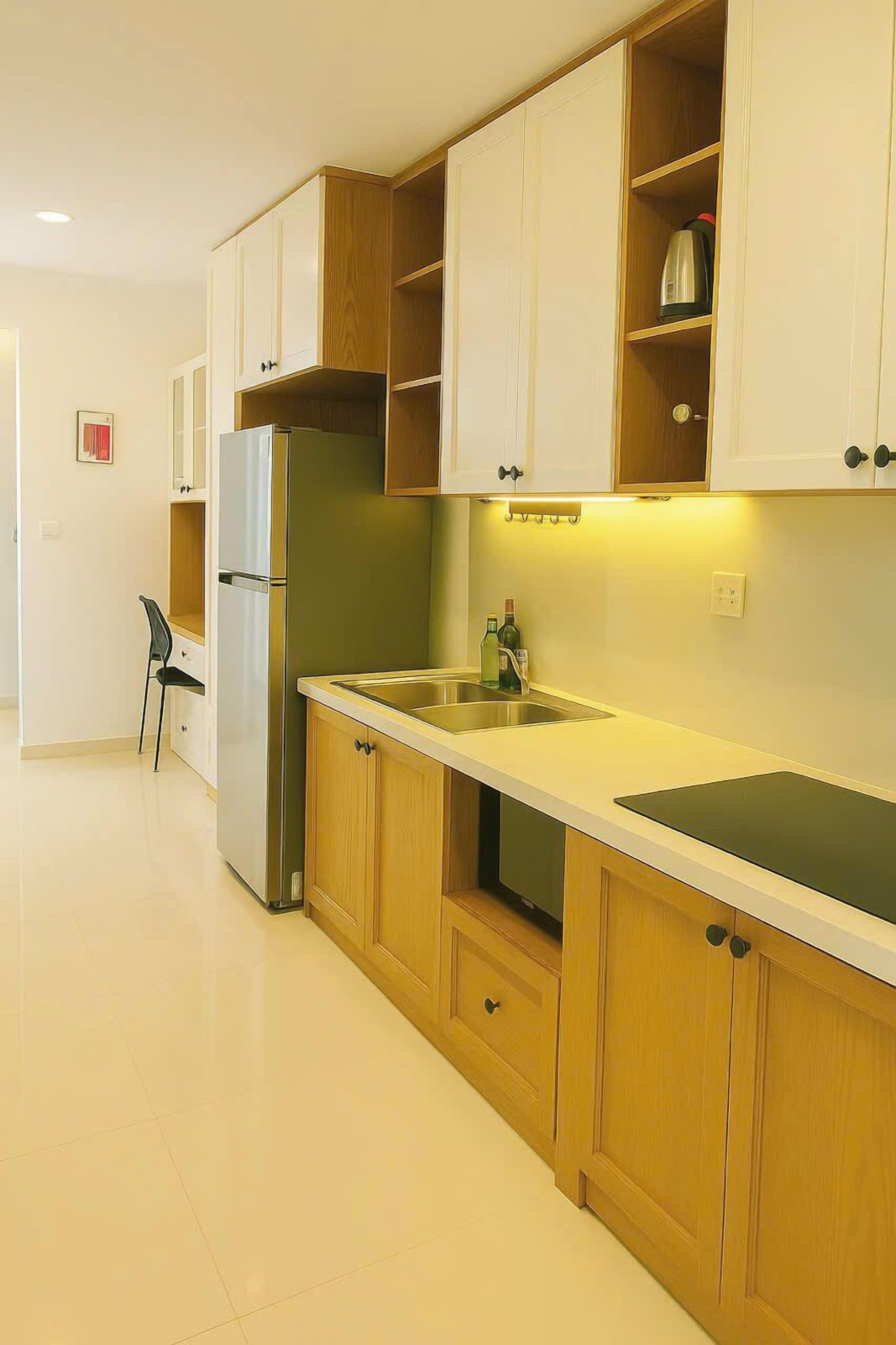 Una cocina moderna con armarios de madera, un refrigerador de acero inoxidable y un lavamanos.