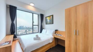 Une chambre d’hôtel moderne avec un grand lit, un bureau en bois, une armoire et une vue sur la ville.
