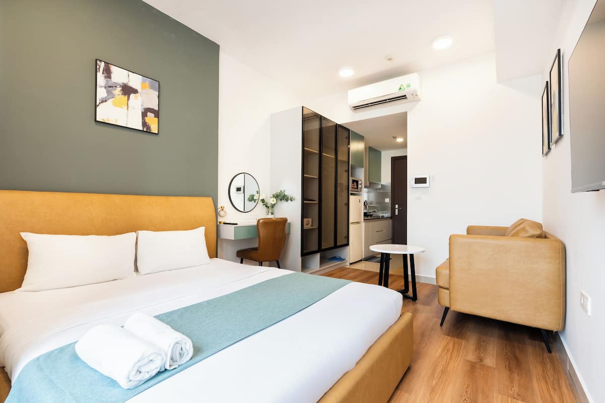 A hotel room with a large bed, a desk, a chair, and a small table.