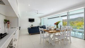 A modern kitchen with a dining area, a sofa, and a TV.