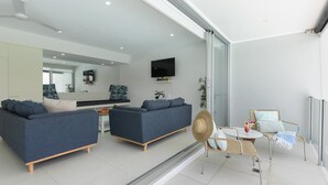 A modern living room with two sofas, a TV, and a dining area with a table and chairs.