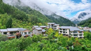 Un pueblo montañoso con edificios modernos, abundante vegetación y un valle.