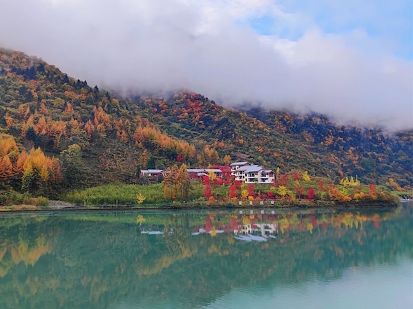 A lakeside property with a reflection of the surrounding autumn foliage. - Summergarden Hotel  (Ngawa Autonomous Prefecture)