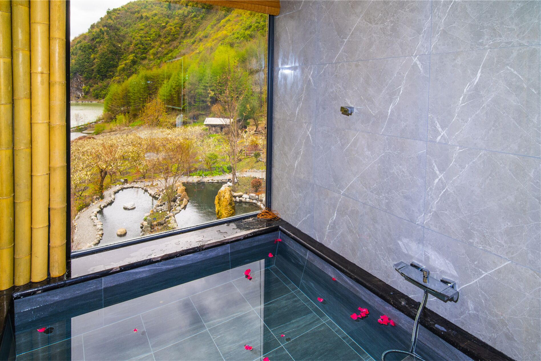 A bathroom with a large window, a bathtub, and a shower area.