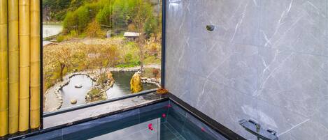 A bathroom with a large window, a bathtub, and a shower area.