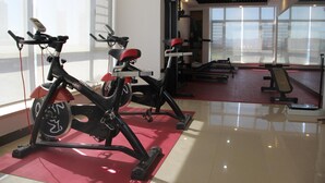 Une salle de sport équipée de vélos d’appartement, d’appareils de musculation et d’un espace avec un tapis rouge.