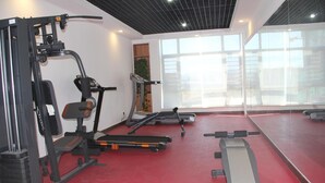 Et fitnessrum med træningsudstyr, et løbebånd og en spejlvæg.