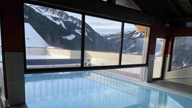 A swimming pool with a view of snow-covered mountains through large windows. - Grand Lodge GRA13 SPA & MOUNTAIN 6 Pers. (Châtel)