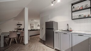 Une cuisine moderne avec des meubles gris, un réfrigérateur en acier inoxydable et un plan de travail en marbre.