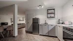 Une cuisine moderne avec un parquet en chevrons, des appareils électroménagers en acier inoxydable et un four encastré.