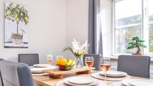 A dining area with a wooden table set for four, a vase with flowers, and a bonsai tree by the window. - Stone cottage - In the Heart of Stamford (Stamford)