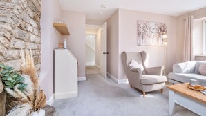 A cozy living room with a stone wall, a white sofa, a beige armchair, and a wooden coffee table. - Stone cottage - In the Heart of Stamford (Stamford)