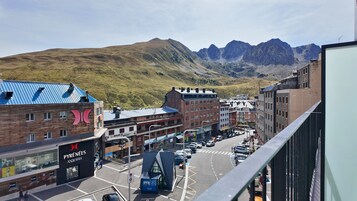 A street view with buildings, a clear sky, and mountains in the background.