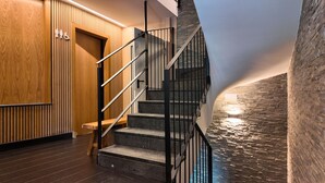 A modern staircase with a wooden door and a stone wall.