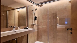 Ein modernes Badezimmer mit einer Duschkabine aus Glas, einem großen Spiegel und einem weißen Waschbecken.