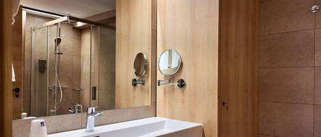 A modern bathroom with a large mirror, a sink, and a shower.