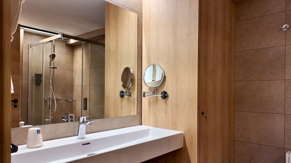 A modern bathroom with a large mirror, a sink, and a shower. - Hotel Catanies (Pas de la Casa)