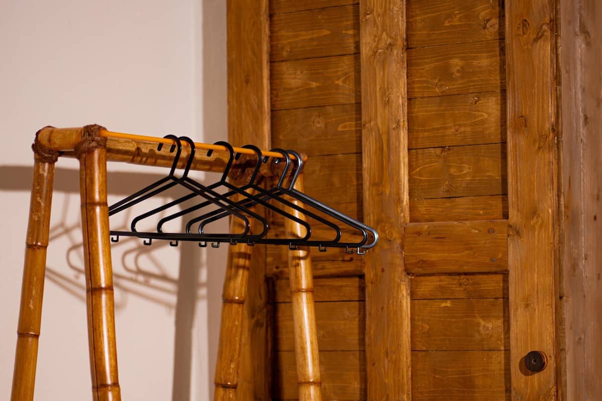 A wooden wardrobe with a bamboo hanger rack in front.