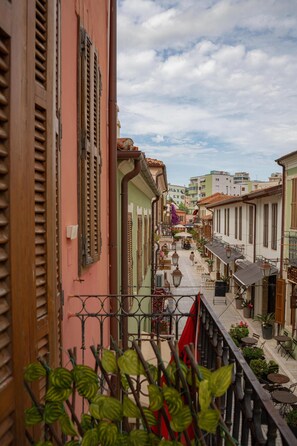 A narrow street with buildings on either side, balconies, and outdoor seating areas. - Buddha House Hotel and Cocktail Bar (Vlorë)