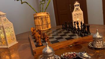 A chessboard set on a wooden table with a lamp, a decorative lantern, and a bamboo plant.