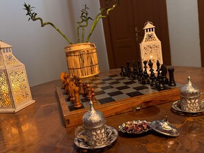 A chessboard set on a wooden table with a lamp, a decorative lantern, and a bamboo plant. - Buddha House Hotel and Cocktail Bar (Vlorë)