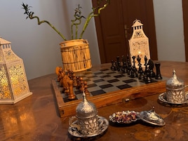 A chessboard set on a wooden table with a lamp, a decorative lantern, and a bamboo plant.