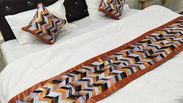 A bed with a patterned bedspread and two decorative pillows.