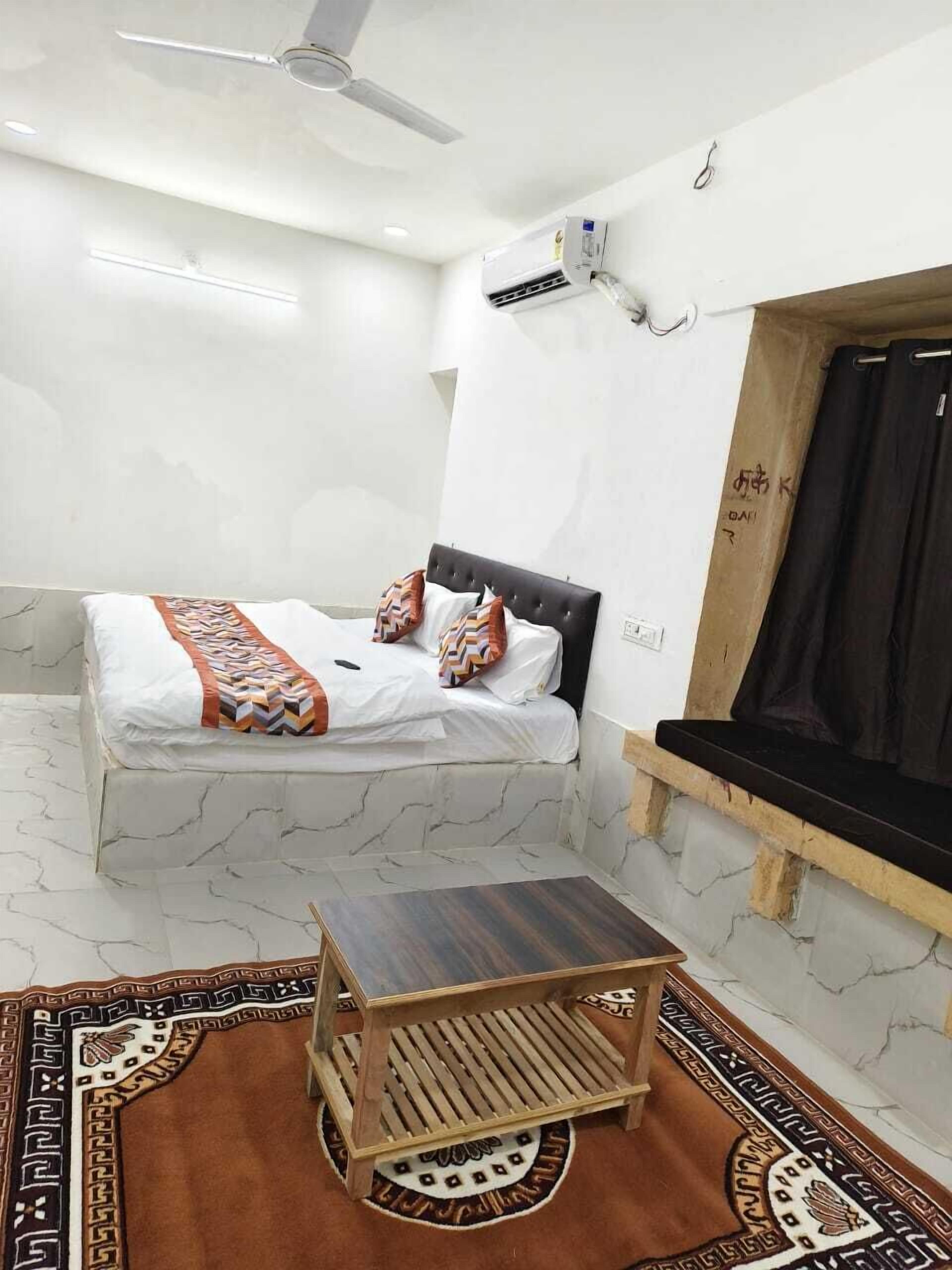 A small, clean room with a bed, a small table, and a ceiling fan.