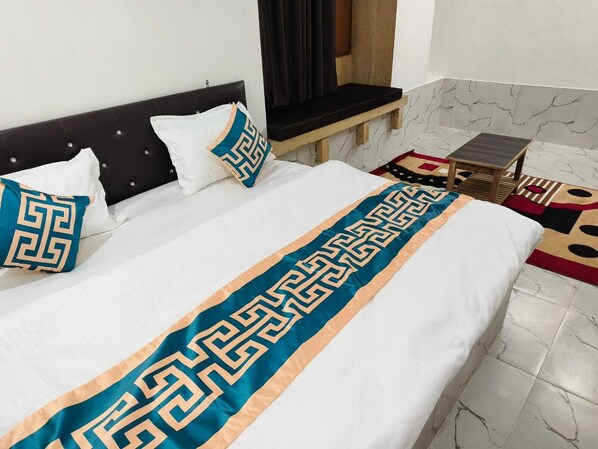 Un lit bien fait, agrémenté d’une couvre-lit décorative, d’une tête de lit et d’une fenêtre avec des rideaux.