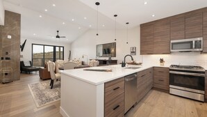 Une cuisine moderne dotée d’un grand îlot central, d’appareils électroménagers en acier inoxydable et de meubles de rangement en bois.