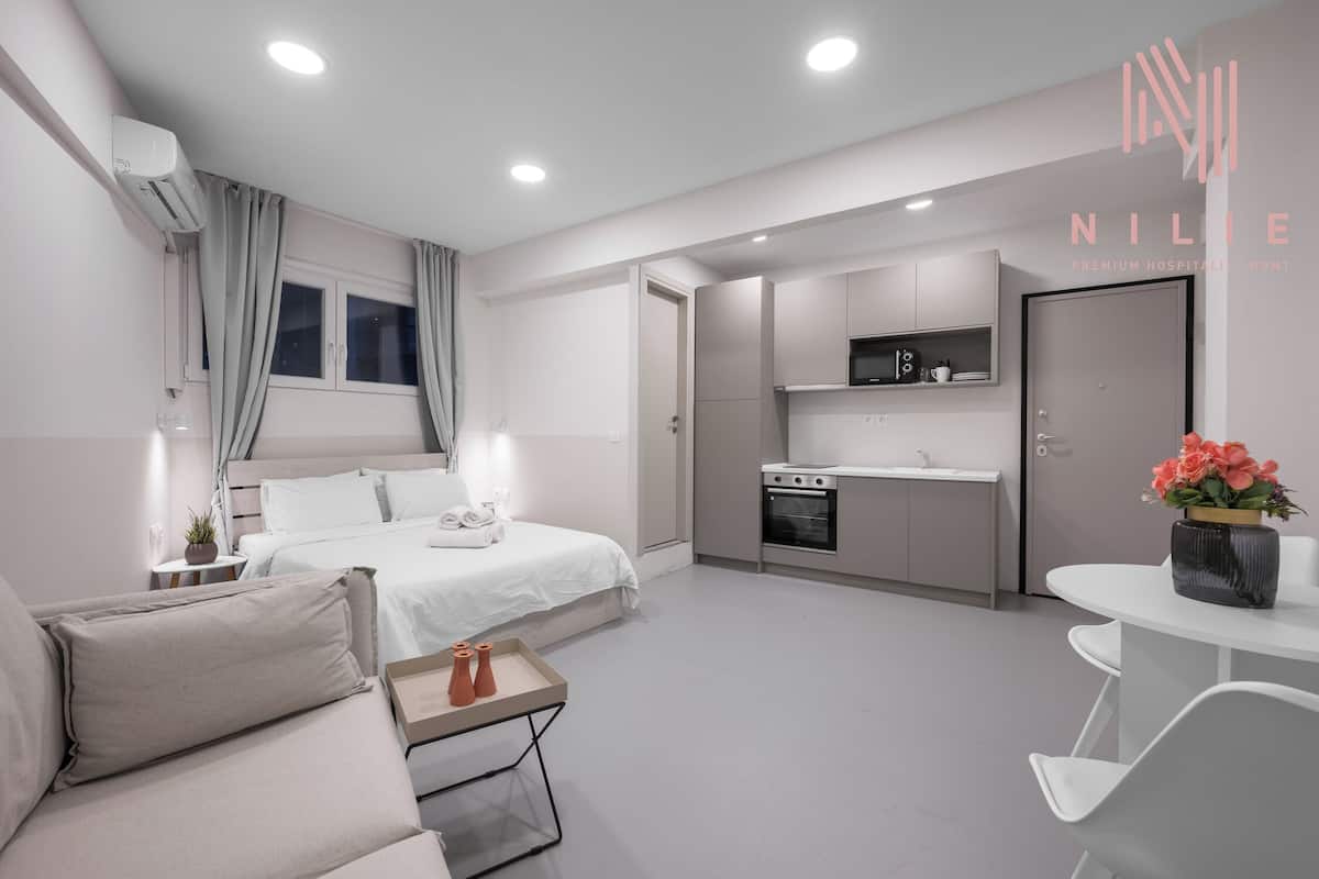 Une chambre d’hôtel moderne équipée d’un lit, d’une table de chevet et d’une petite kitchenette.