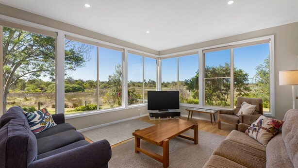 A spacious living room with large windows, a flat-screen TV, a wooden coffee table, and two sofas. - Pelican Point- Located next to Edwards Point Wildlife Reserve (St Leonards)