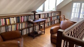 A library with bookshelves, a wooden table, and leather chairs.