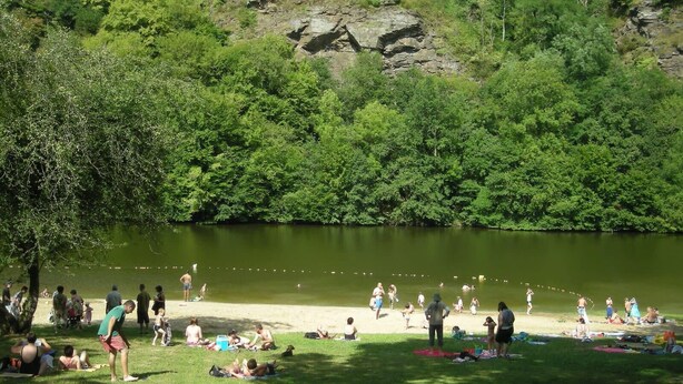 A lakeside park with people relaxing on the grass and by the water.