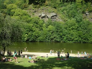 A lakeside park with people relaxing on the grass and by the water. - Villa le Roche du Ris -  10-12 personnes (Baraize)