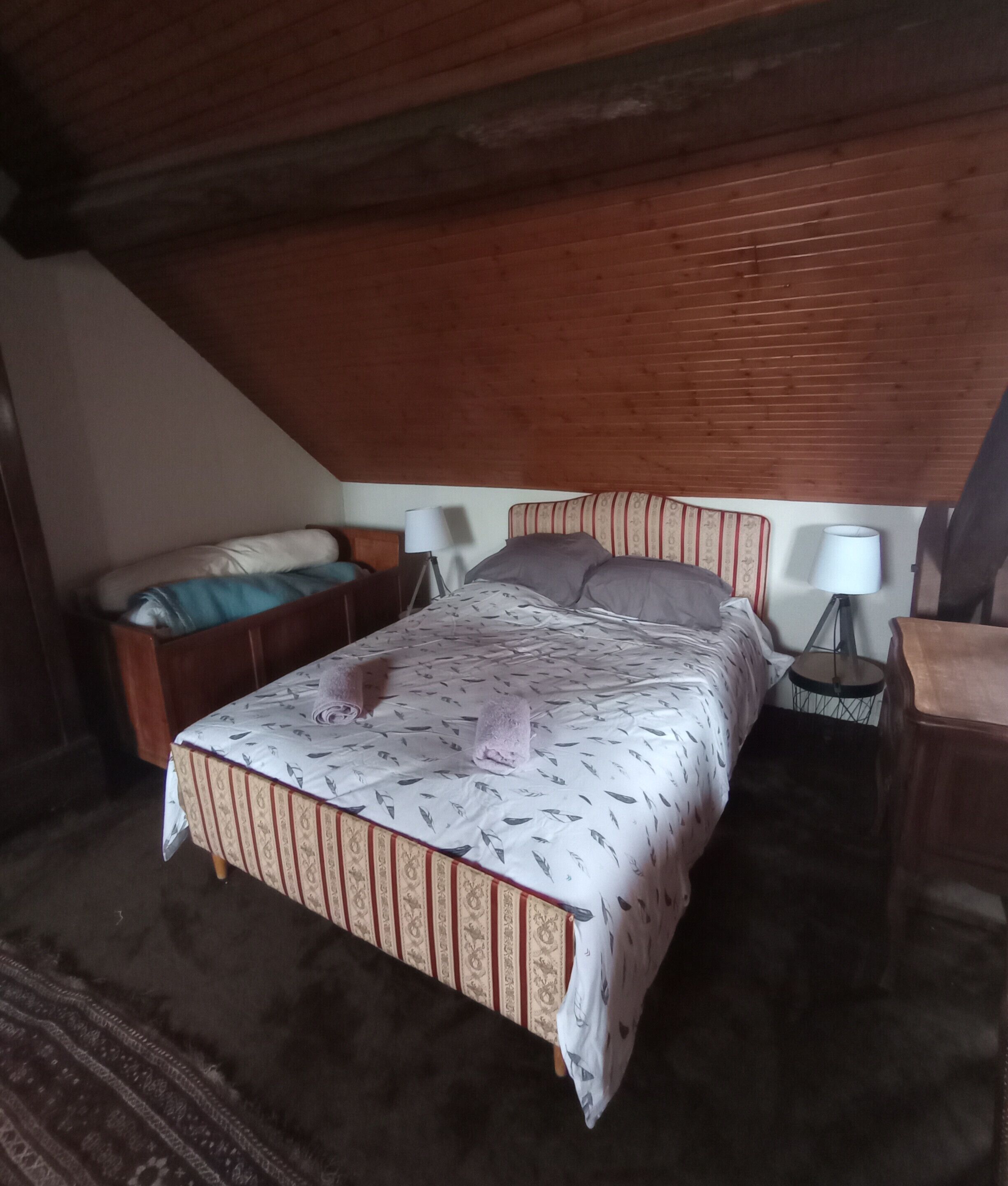 A bedroom with a bed, two bedside tables, a lamp, and a bench.