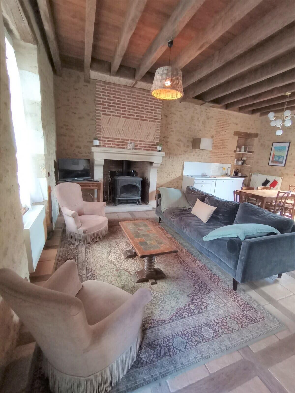 Un salon chaleureux avec une cheminée, un canapé, un téléviseur et un coin repas.