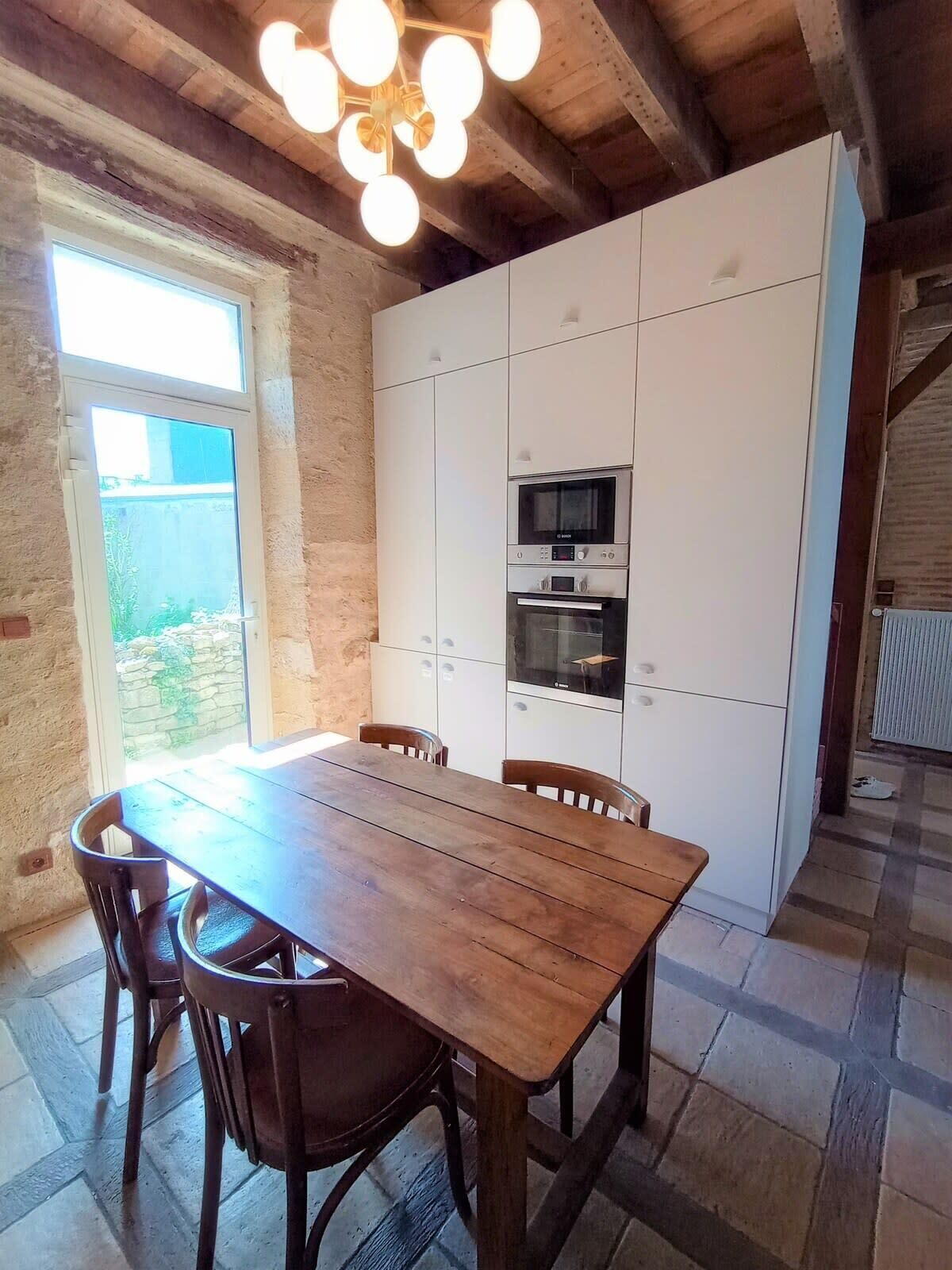 A kitchen with a wooden table and chairs, white cabinets, and a built-in oven.